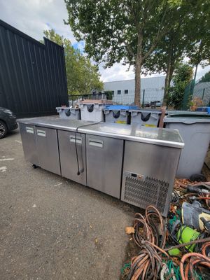 un tas de déchets par terre, à côté d'un réfrigérateur