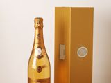 des bouteilles de champagne posées sur une table en bois, à côté d'un coffret doré