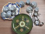 a green plate with a flower design on it next to a plate with spoons and spoon resters