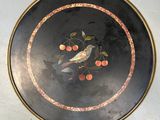 a black plate with a bird and cherries on it