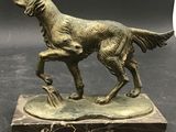 bronze statue of a dog on a marble base on a black background