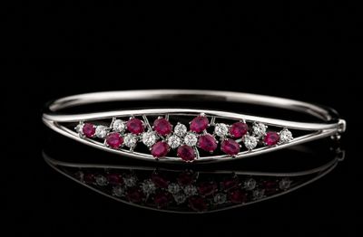 un gros plan d'une bague sertie de diamants et de rubis posée sur une surface noire