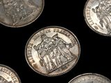 several silver coins are arranged in a row on a black surface