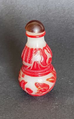 un petit vase rouge et blanc orné d'un oiseau