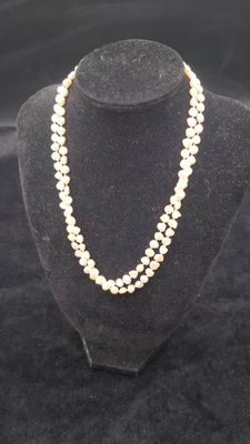 a white pearl necklace on a mannequin with a gold clasp