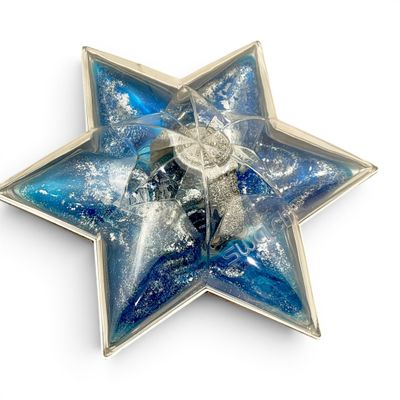 a blue and silver star shaped brooch on a white surface
