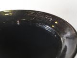 a close up of a black vase on a white table