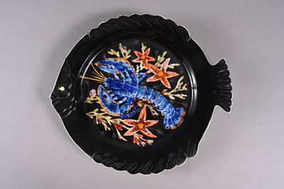 une assiette noire ornée de fleurs bleues et orange