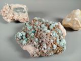 three different colored rocks on a gray surface with a rock in the background