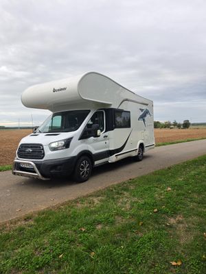 an rv parked on the side of a road next to a field