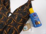a bottle of sunscreen sitting next to a necktie