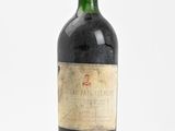 an old bottle of wine sitting on top of a white surface