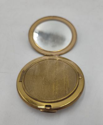 un gros plan d'un miroir de poche doré posé sur une surface blanche