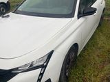a white car is parked in the grass outside of a house