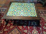 une table basse avec un plateau en carreaux colorés, posée sur un tapis