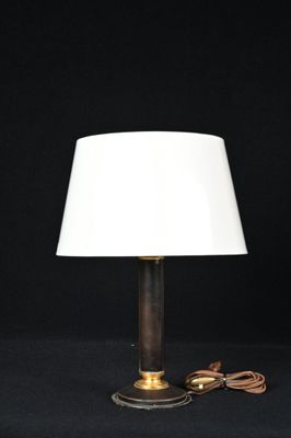 une lampe de table en laiton avec un abat-jour blanc sur fond noir