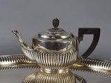 a silver tea pot on a silver tray on a table