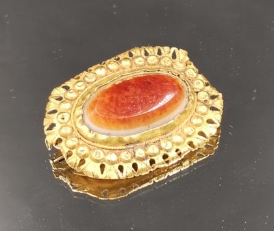 broche plaquée or ornée d'une pierre rouge en son centre