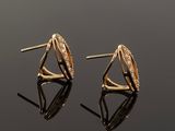 a pair of gold earrings with diamonds on a black surface