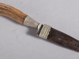un couteau avec un manche en bois sur une surface blanche