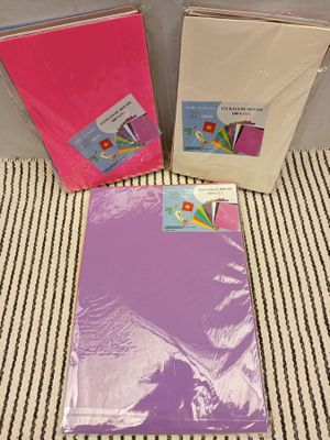 three different colored cards and envelopes sitting on a striped surface