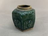 a green vase with a design on it on a white surface