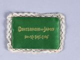 a green and white embroidered badge with gold writing on it