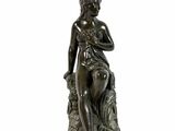 une photo d'une statue en bronze représentant une femme assise sur une souche d'arbre