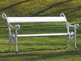 un banc blanc posé au milieu de la pelouse