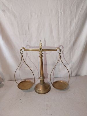 une vieille balance en laiton sur laquelle se trouvent deux plateaux vides