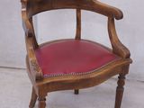 une chaise en bois avec une assise en cuir rouge posée sur un sol en béton
