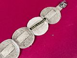 a close up of a silver bracelet on a pink surface
