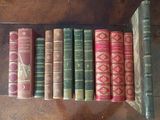 several old books are lined up on a shelf on a table