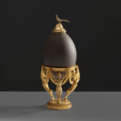 an egg with a bird on top of it sitting on top of a table