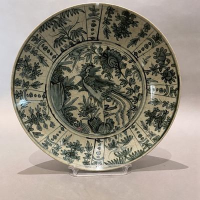 une assiette ornée d'un oiseau, posée sur un socle