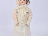 porcelain doll of a woman in a white dress and bonnet