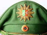 a green hat with a gold sun badge on it