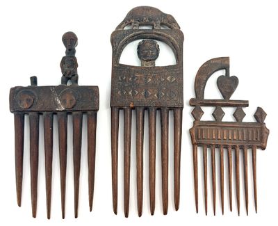 three pieces of antique hair combs are displayed on a white surface