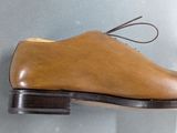 brown leather shoes hanging on a wall on a gray wall
