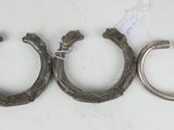 three antique silver horseshoes are sitting on a white surface