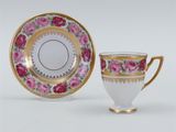a white cup and saucer with pink roses on a gold rim