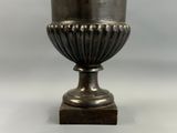 an antique silver vase on a wooden base on a white background
