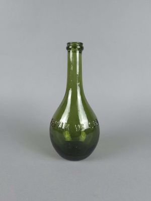 une bouteille en verre vert posée sur une surface grise