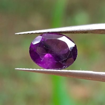 une personne tenant une pince ornée d'une pierre précieuse violette