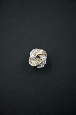 a gold and diamond knot ring on a black surface
