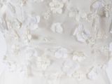 the back of a wedding dress with white flowers on it
