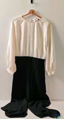 une robe noire et blanche suspendue à un cintre près d'un mur blanc