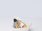 petit bol blanc orné de rayures colorées, posé sur une surface blanche