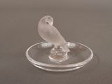 a glass bird sitting on top of a glass plate