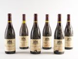 six bottles of wine are lined up in a row on a white surface